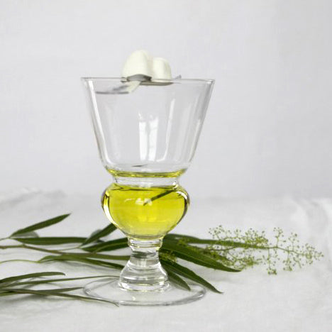 Absinthe glass, spoon on top with sugar cube skull, white background, scattered green leaves