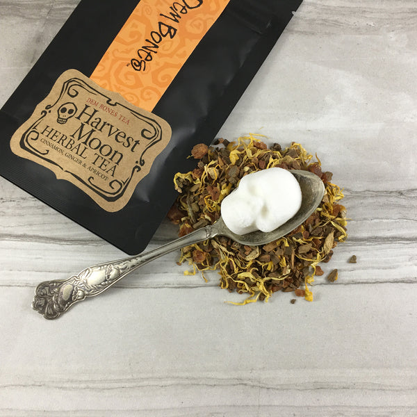 Apricot Cinnamon Tea in pile with Silver spoon and skull sugar cube, Tea in bag reads: DemBones Tea, Harvestt Moon Herbal Tea, 