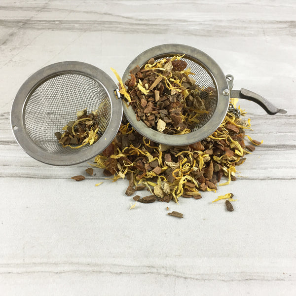 Harvest Moon Herbal Tea spilling gout of tea ball on white tile background, Cinnamon Tea, DemBones Shoppe