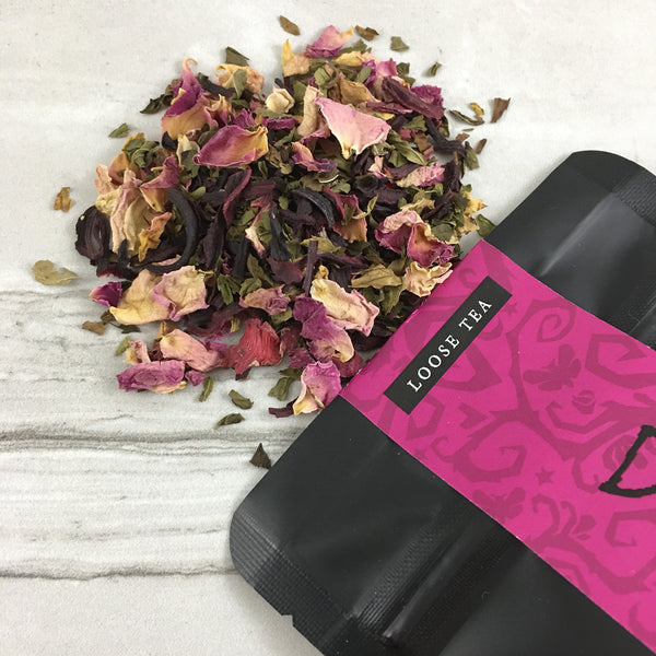 Rose tea spilled on marble table, black bag with deep pink label, loose tea, gothic design 